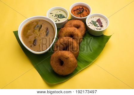 south indian food called vada sambar or sambar vada or wada, served with coconut, green and red chutney over fresg banana leaf, selective focus
