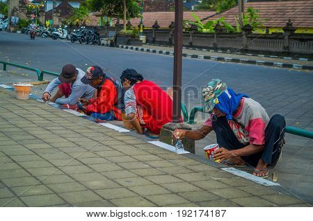 BALI, INDONESIA - MARCH 08, 2017: Unidentified group of people painting the sidewalk outside of the royal temple of Mengwi Empire located in Mengwi in Bali, Indonesia.