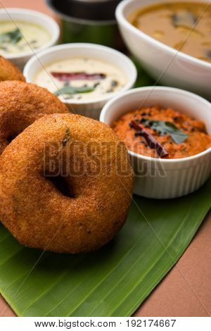 south indian food called vada sambar or sambar vada or wada, served with coconut, green and red chutney over fresg banana leaf, selective focus