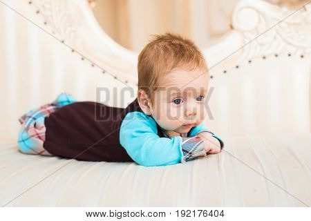 Adorable baby boy with red hair and blue eyes. Newborn child lyling in couch