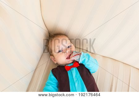 Adorable baby boy with red hair and blue eyes. Newborn child lyling in couch