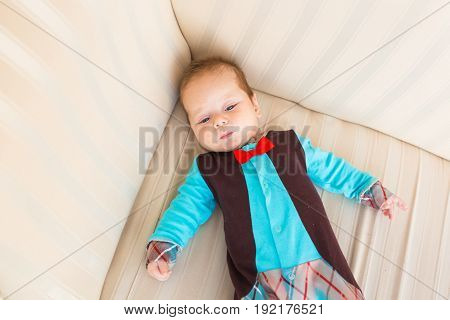 Adorable baby boy with red hair and blue eyes. Newborn child lyling in couch
