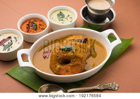 south indian food called vada sambar or sambar vada or wada dipped in sambar with coconut, green and red chutney and south indian style hot coffee, selective focus
