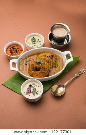 south indian food called vada sambar or sambar vada or wada dipped in sambar with coconut, green and red chutney and south indian style hot coffee, selective focus