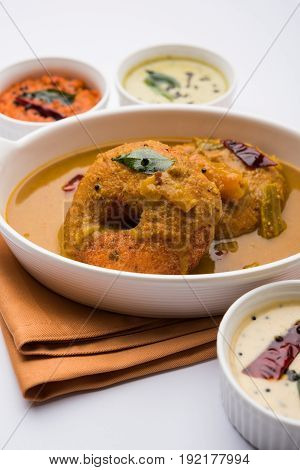 south indian food called vada sambar or sambar vada or wada dipped in sambar with coconut, green and red chutney and south indian style hot coffee, selective focus