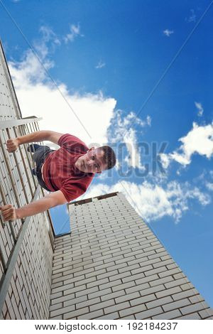 Roofer descends the stairs from the roof of the building. Courage and adrenaline.