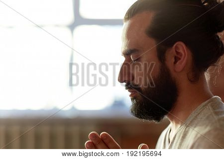 religion, faith and people concept - close up of man meditating at yoga studio