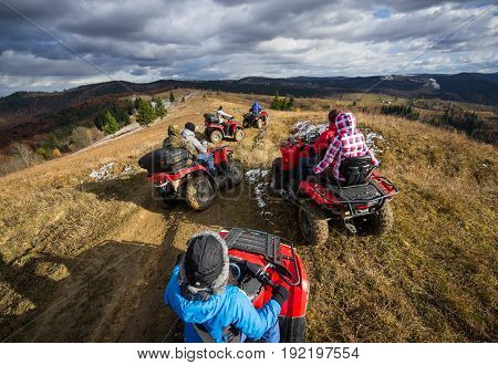 Top View Of A Group Of People Riding A Off-road Vehicles On A Mountain Road Under A Sky With Clouds