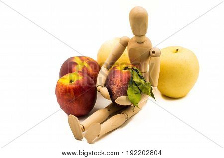 wooden man puppet sitting hugging a nectarine on white background