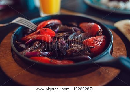Mexican fajitos in a frying pan on a table.