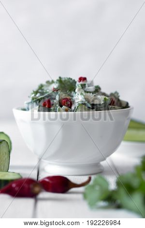 Cucumber salad with coriander and yogurt dressing on the white wooden background