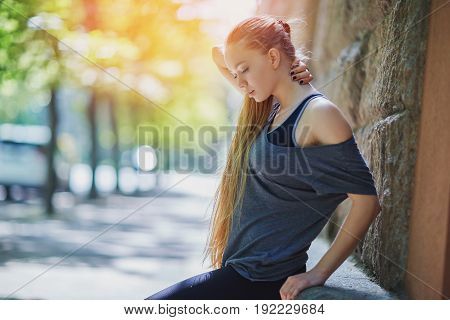 Sports girl doing stretching near building and running down the street in the morning