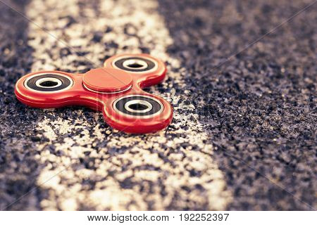 Popular spinner gadget in 2017 on a blue and white background. Modern red plastic spinner fidget game for young people.