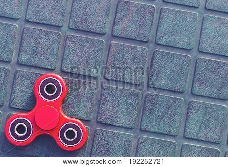 Top view of the popular red spinner gadget in 2017 on the blue-green background.