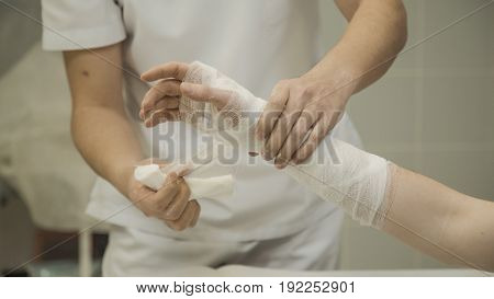 Doctor puts gypsum pad on patient's hand in hospital