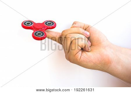 Closeup of a young caucasian man playing with red fidget spinner on white background. Popular spinner gadget in 2017