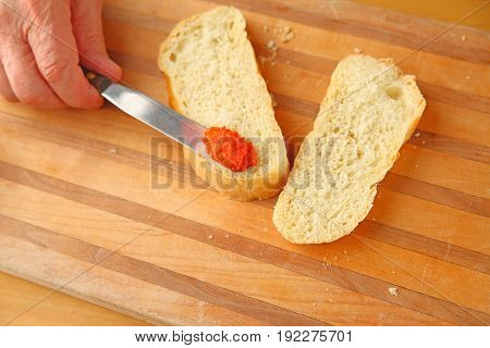Man spreads bell pepper tapenade on sourdough bread with copy space
