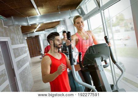 Attractive woman working cardio exercises with personal trainer in gym