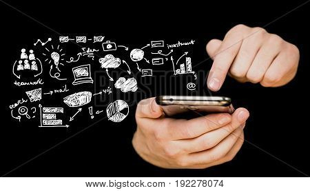 Man's hands using a smartphone on a black background with business finanacial icons.