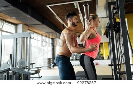 Woman doing squats in gym with her personal trainer