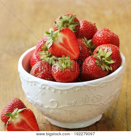 Fresh strawberries in bowl on wood table, organic garden berries .