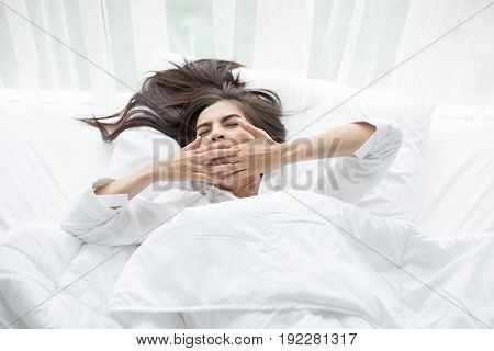 Asian woman Beautiful young smiling woman sitting on bed and stretching in the morning at bedroom after waking up in her bed fully rested