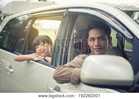 happy little girl with asian family sitting in the car for enjoying road trip and summer vacation
