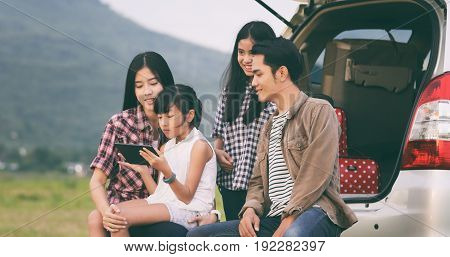 Happy little girl e with asian family sitting in the car for enjoying road trip and summer vacation in camper van