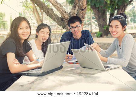 Asian Group of students smiling and sharing with the ideas for working on the campus lawn