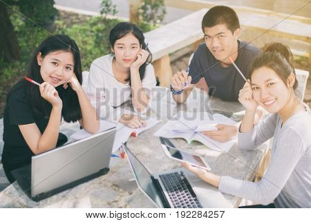 Asian Group of students smiling and sharing with the ideas for working on the campus lawn