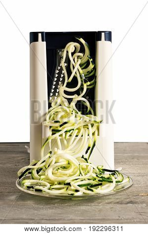 Front view of vegetable spiralizer making raw zucchini noodles (zoodles) .
