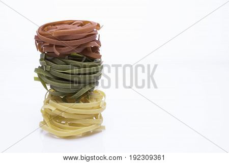 Different color of Italian uncooked pasta fettuccine on white reflection background close up. Space for text.