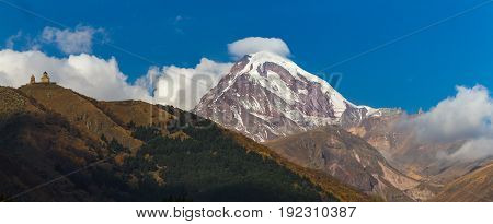 Ancient Trinity Church And A Snow Capped Mountain Of Kazbegi