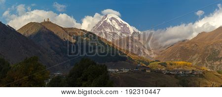 Ancient Trinity Church And A Snow Capped Mountain Of Kazbegi