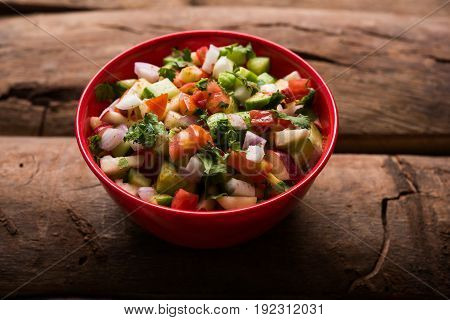 Indian Green Salad also known as Kachumber is a colourful salad dish in Indian cuisine consisting of fresh chopped tomatoes, cucumbers, onions, and sometimes, chili peppers. selective focus