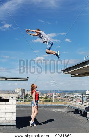 A loving couple of roofer on the roof. The girl watches as her boyfriend jumps from roof to roof. Romance and courage. An unusual date.