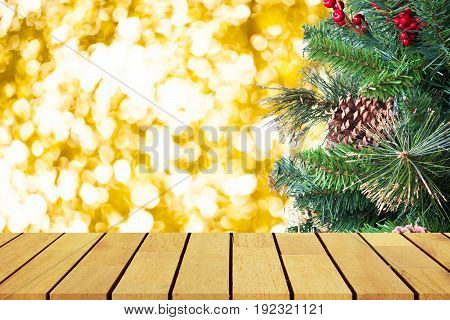 Prespective empty wooden table in front of christmas tree and gole bokeh background for product display montage or design layout.