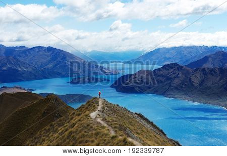 Panoramic view of lake Wanaka, New Zealand. Wanaka lake and woman in red shit standing on the top of mountain