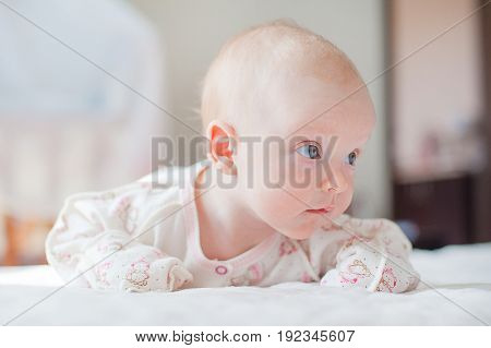 The  little baby girl crawls on the white bed