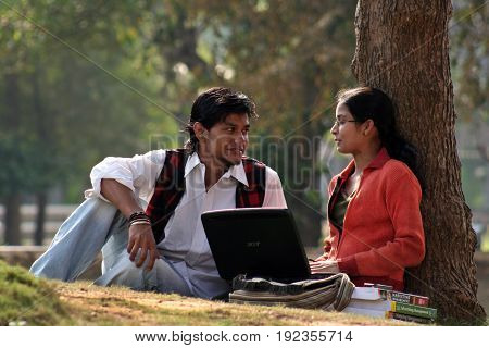 KOLKATA, DECEMBER 03, 2008: A Couple of young Indian College student is discussing with laptop and books at the campus ground on December 03, 2008 in India.