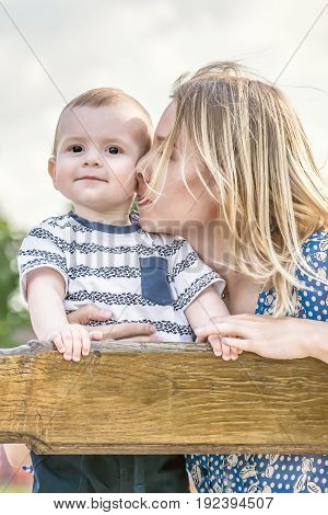 Beautiful happy mather with baby boy outdoor on nature at sunny summer say
