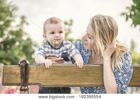 Beautiful happy mather with baby boy outdoor on nature at sunny summer say
