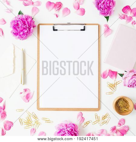 Workspace with clipboard, notebook, pen, envelope and pink roses on white background. Flat lay, top view.