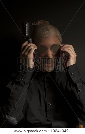 criminal bandit man wearing a stocking mask holds a gun in his hand on black background