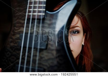 Red Haired Punk Girl Wear On Black With Bass Guitar At Abadoned Place. Portrait Of Gothic Woman Musi