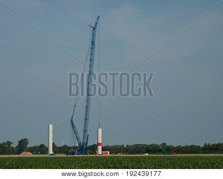 building a new wind power plant with a big blue crane Kalkar Germany