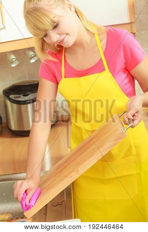 People housework and housekeeping concept. Woman doing the tidying up in kitchen cleaning wooden cutting board with rag sponge