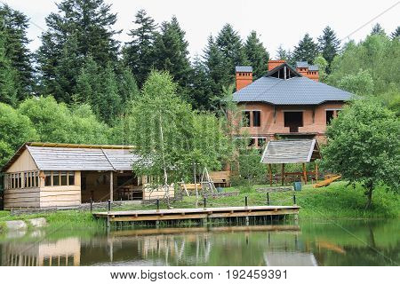 Modern cottage and a gazebo on shore of lake in Ukrainian Carpathians
