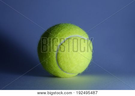 Single tennis ball in studio with blue lighting