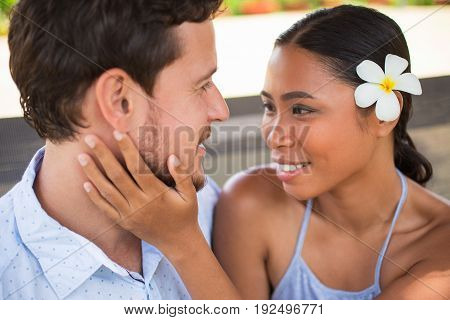 Closeup of smiling young Asian woman embracing boyfriend neck